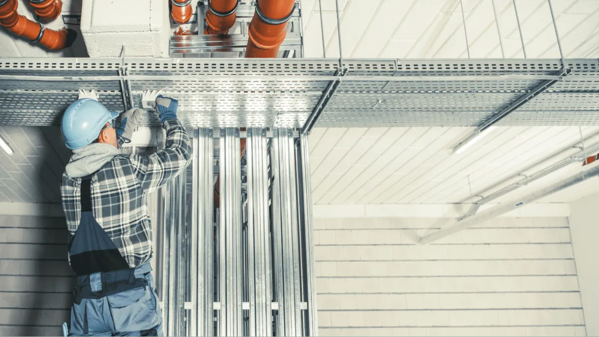 Worker installing metal framework overhead